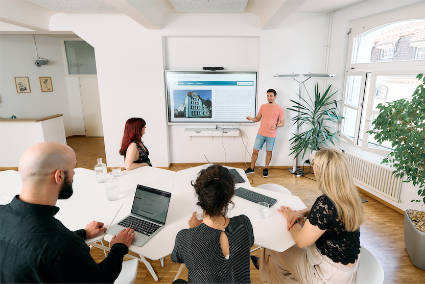 Ein Meerting-Raum mit Stehtischen und Monitor